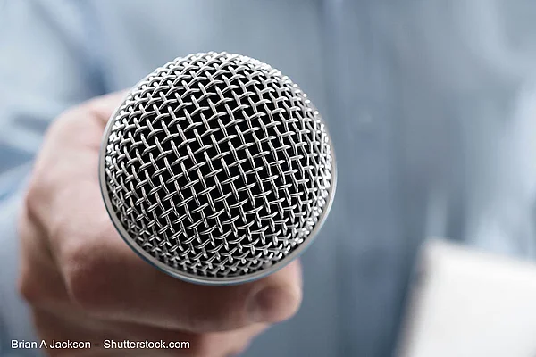 Mikrofon wird in Richtung Kamera gehalten