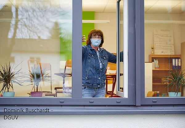 Frau mit Maske öffnet Fenster