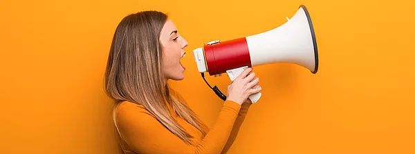 Junge Frau schreit durch ein Megaphon