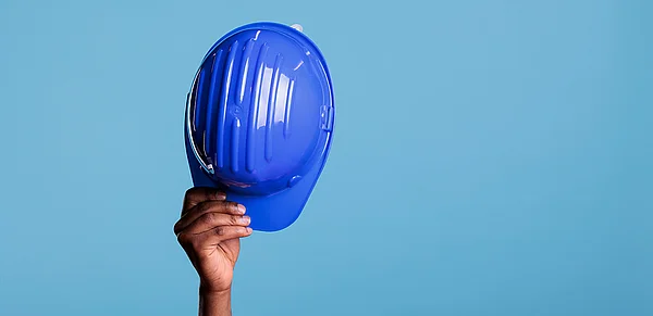 Hand hält blauen Schutzhelm