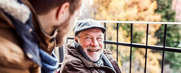 alter Mann lächelt jüngeren Mann an