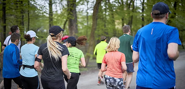 Eine Menschengruppe joggt im Wald.
