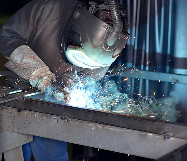 Schweißer mit Schweißgerät und Schutzmaske.