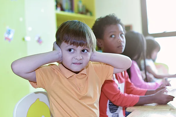 Junge im Kindergarten hält sich die Ohren zu