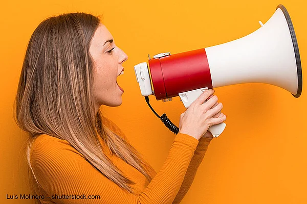 Junge Frau ruft durch ein Megafon.