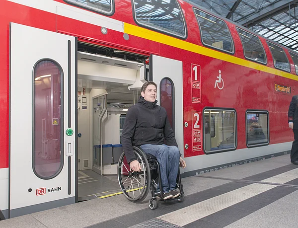 Junger Mann im Rollstuhl steigt aus Bahn aus