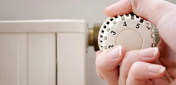 Hand dreht am Heizungsregler