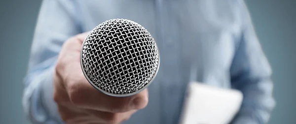 Hand hält Mikrofon in der Hand