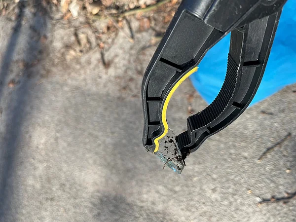 Greifzange mit einem Glasscherben.